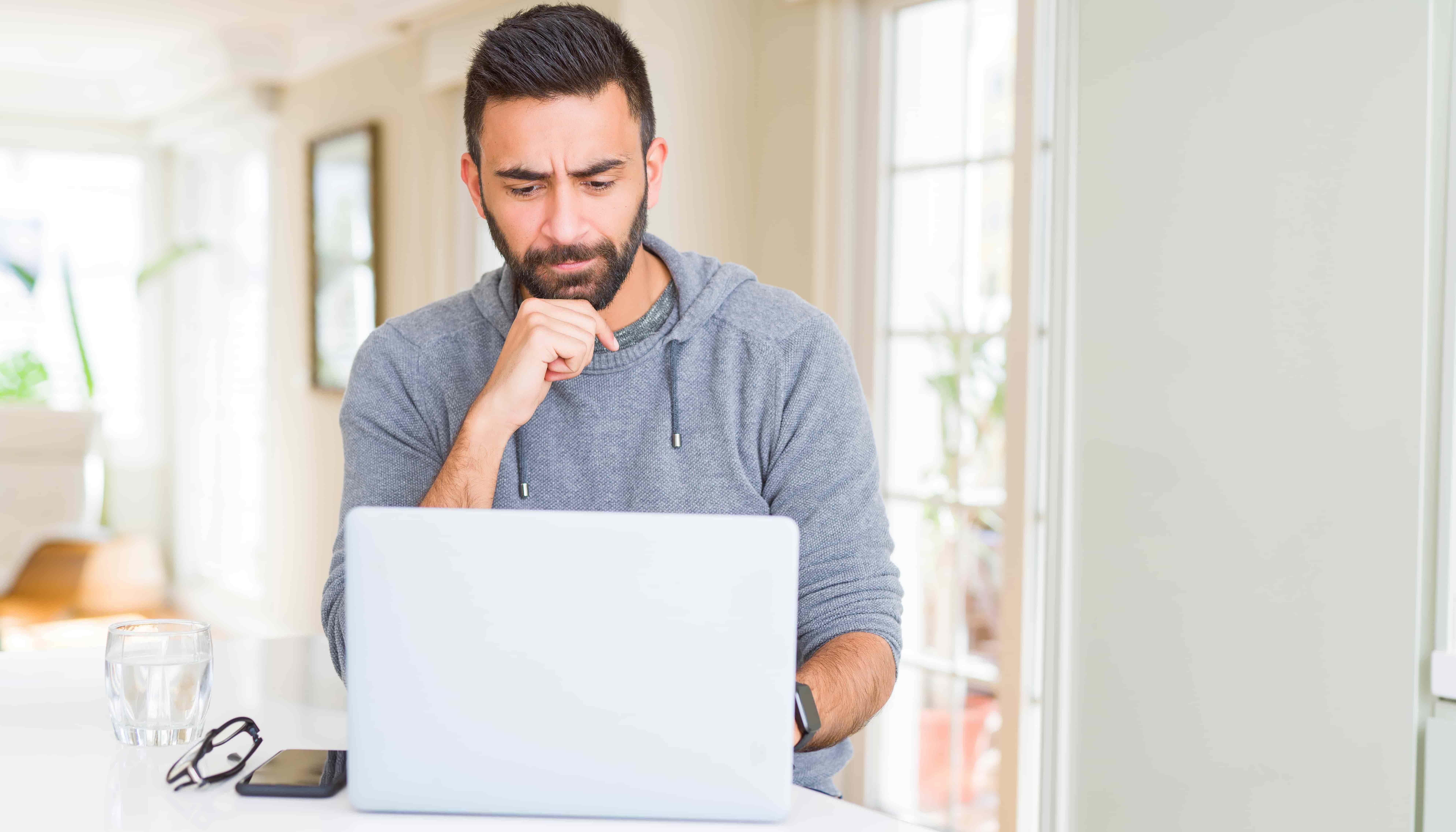 Handsome hispanic man working using computer laptop serious face thinking about question, very confused idea
